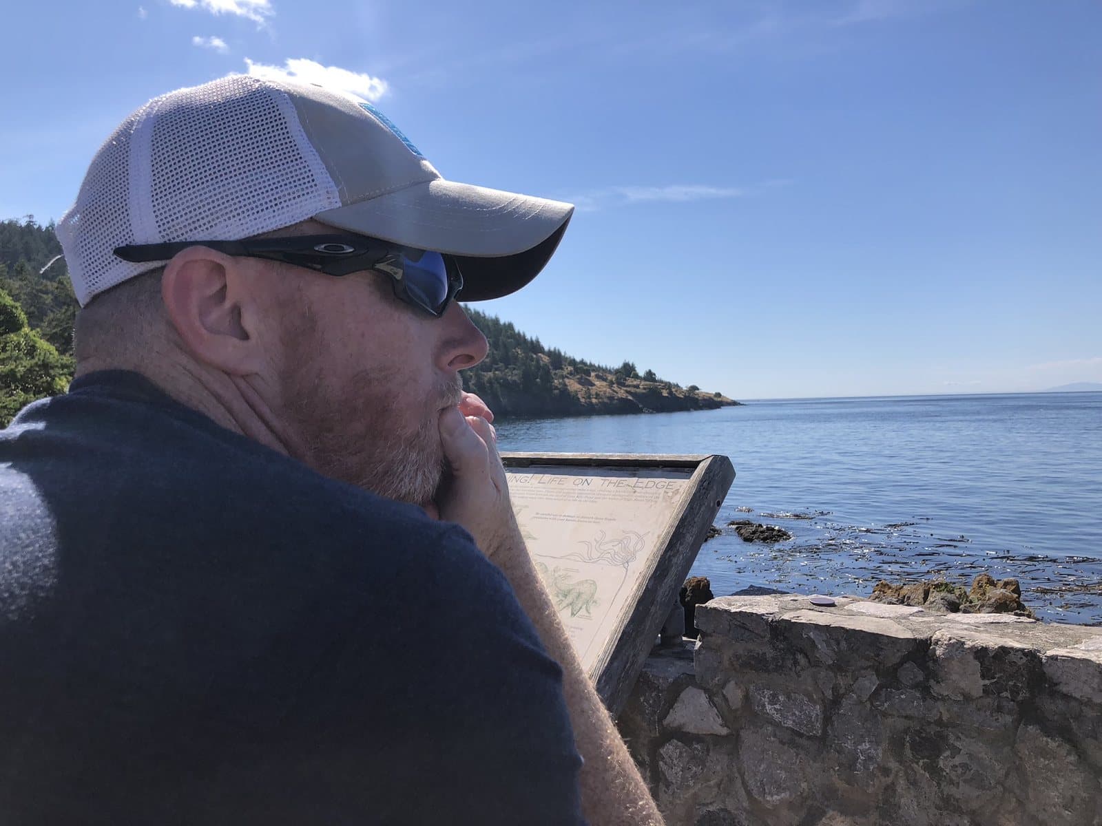 Matt reading outdoors, looking out across the water.